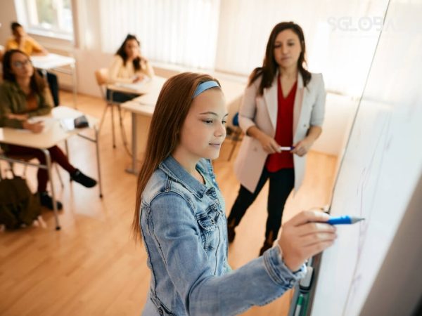 Nữ sinh viết bài thuyết trình về chi phí du học Mỹ trên bảng lớp.