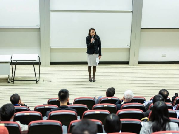 Giảng viên đang đứng trên bục giảng trong một hội trường đại học lớn tại Canada, trước hàng ghế sinh viên đang lắng nghe. chuẩn bị tâm lý du học canada
