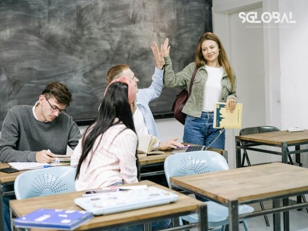 Nhóm sinh viên giao lưu, bắt tay làm quen trong lớp học – phản ánh bước đầu hòa nhập của du học sinh tại Canada.