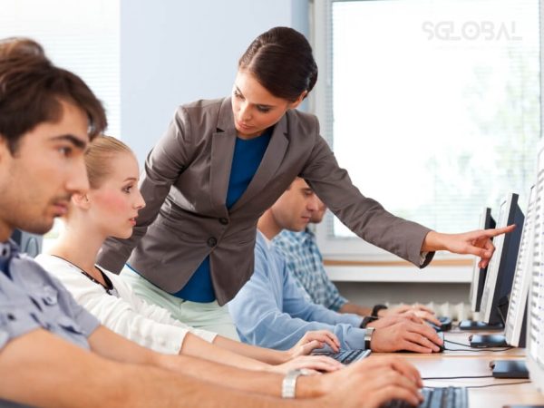 Lớp học hiện đại với giáo viên đang hướng dẫn sinh viên làm việc nhóm, thể hiện phương pháp đào tạo thực tiễn tại Canada.