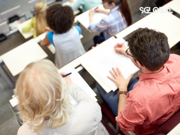 Góc nhìn từ phía sau lớp học bậc cao đẳng – đại học tại Canada, sinh viên đang chăm chú ghi chép.
