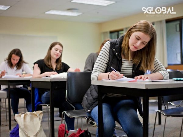Sinh viên nữ ghi chép chi tiết trong lớp học – thể hiện tinh thần học tập nghiêm túc khi du học Mỹ.