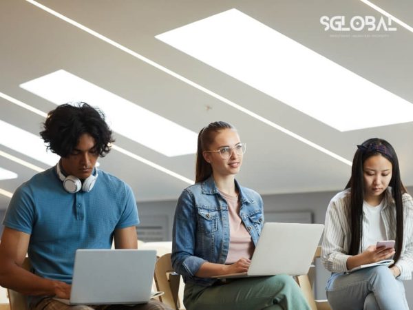 Ba sinh viên quốc tế đang học nhóm tại khu vực học tập chung với laptop cá nhân.