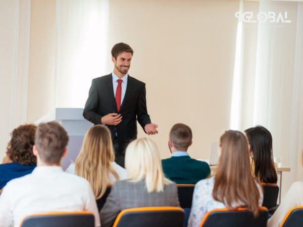 Góc nhìn cận cảnh một lớp học nghề tại Mỹ với giảng viên đang trình bày và sinh viên quốc tế chăm chú theo dõi.