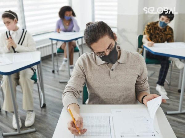 Sinh viên đang làm bài thi trong phòng kiểm tra nghiêm ngặt, phản ánh quy trình học tập và đánh giá thực chất.
