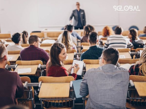 Giảng viên đang giảng bài trước lớp học nghề tại Mỹ, sinh viên chăm chú lắng nghe từ phía sau.