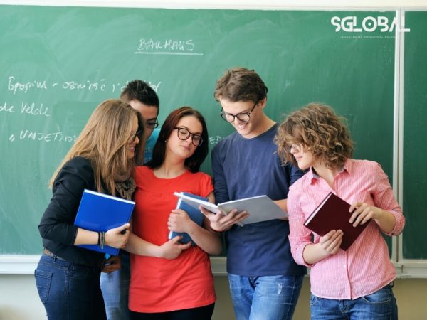 Nhóm sinh viên quốc tế đang trao đổi bài tập trong lớp học tại Đức.