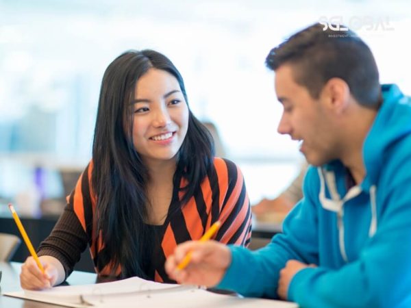 Một nam sinh viên đang được nữ giảng viên hỗ trợ học tập, biểu tượng cho chất lượng giảng dạy sát sao tại Canada.