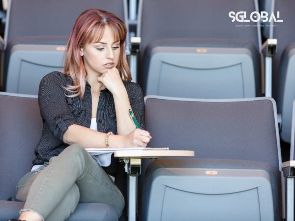 Một nữ sinh quốc tế đang chăm chú ghi chép trong buổi hướng dẫn xin visa Mỹ tại giảng đường.